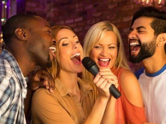 A group of people singing into a microphone Description automatically generated with medium confidence